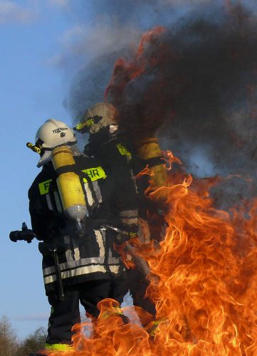 Zwei Feuerwehrmänner der Freiwilligen Feuerwehr Hausen löschen im Rahmen ihrer Mitgliedschaft im Verein einen Brand.